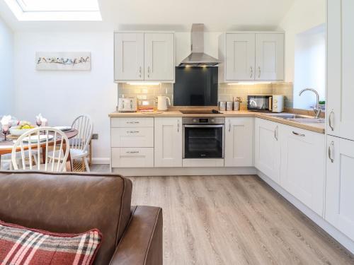 a kitchen with white cabinets and a couch and a table at Tan Llech in Harlech