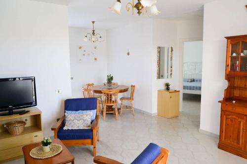 uma sala de estar com uma televisão e uma mesa de jantar em Casa Clarissa em Marina di Casalvelino