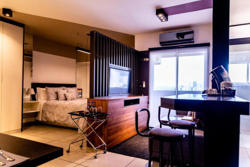 a bedroom with a bed and a desk with a television at Loft Campolim in Sorocaba