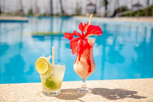 dos cócteles sentados en una mesa junto a una piscina en Ilheus North Hotel, en Ilhéus