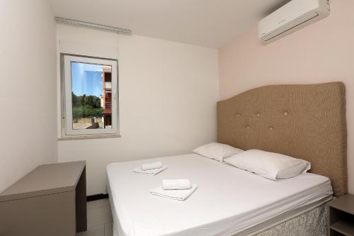 een kleine witte kamer met een bed en een raam bij Waterfront Apartments with Pool in Novalja