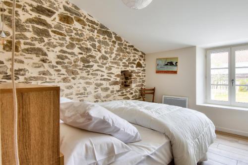 Un dormitorio con una pared de piedra y una cama en Detente dans une jolie maison a Noimoutier en Noirmoutier-en-l'lle