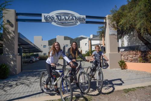 zwei Frauen und ein Kind auf Fahrrädern an einer Tankstelle in der Unterkunft Apart Hotel Los alazanes in Capilla del Monte