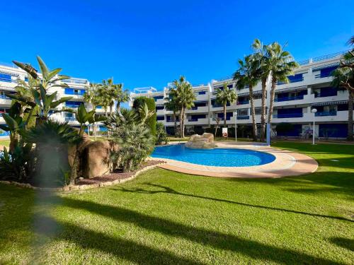 a large apartment building with a swimming pool and palm trees at Casa Monet - La Calma - 4 pools- Big terrace - Orihuela Costa in Playa Flamenca