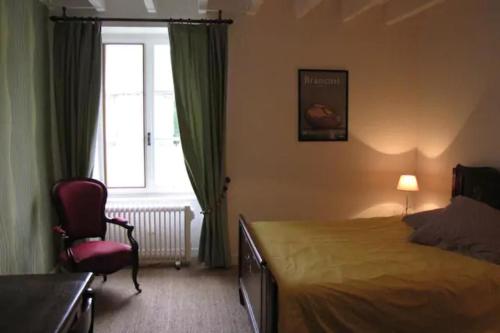 una camera con un letto e una sedia e una finestra di Les Tortues a La Bussière