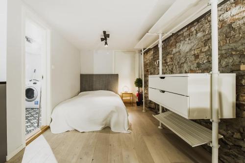 a bedroom with a white bed and a brick wall at Central studio basement apartment in Bergen