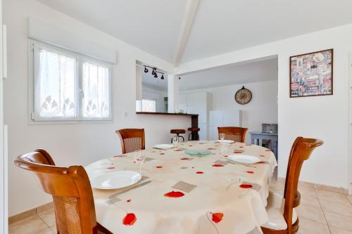 a dining room with a white table with red flowers on it at Le Fenouiller - 6 personnes, Maison Piscine in Le Fenouiller