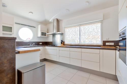 a kitchen with white cabinets and a window at Le Fenouiller - 6 personnes, Maison Piscine in Le Fenouiller