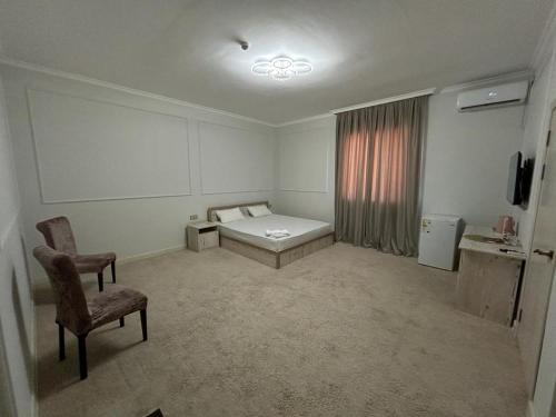 a room with a bed and a chair and a window at Hotel Bereke in Atyrau