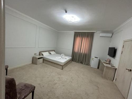 a room with a bed and a television in it at Hotel Bereke in Atyrau