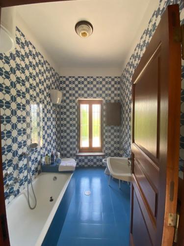 a bathroom with blue flooring and a tub and a window at Casa di don Francesco in Scala