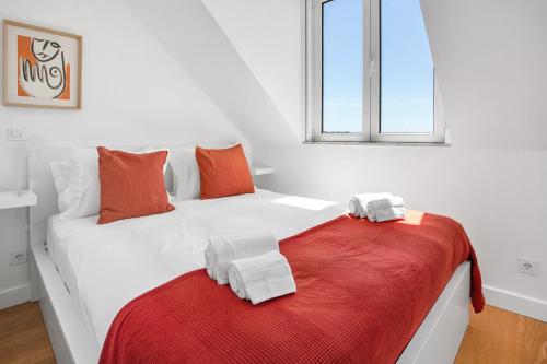 uma cama branca com toalhas cor de laranja e brancas em Brand New River View Apartment Belém - 1 bedroom, A/C em Lisboa