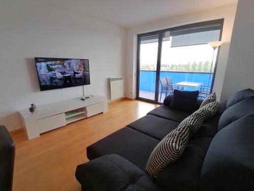 a living room with a black couch and a flat screen tv at Apartment Airport Barcelona Premium in Viladecáns