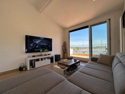 sala de estar con sofá y TV de pantalla plana en L'Atelier Marin sur le Port des Marines en Cogolin