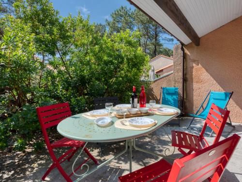 - une table de patio avec des chaises rouges et des bouteilles de vin dans l'établissement Holiday Home Les Cracks-9 by Interhome, à Lacanau-Océan