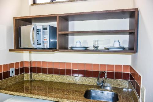 a kitchen counter with a sink and a microwave at Mont Blanc Apart Hotel Nova Iguaçu in Nova Iguaçu