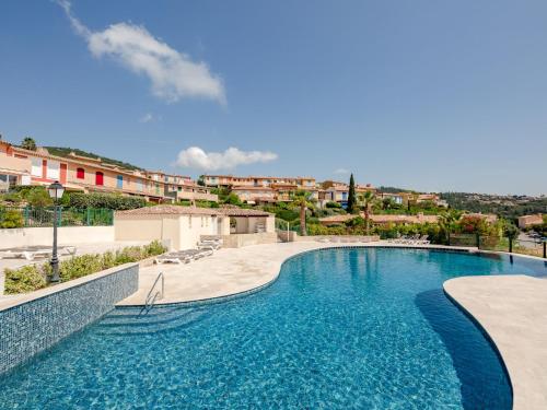 une piscine avec de l'eau bleue devant un immeuble dans l'établissement Apartment Le Petit Village-2 by Interhome, à La Garonnette-Plage