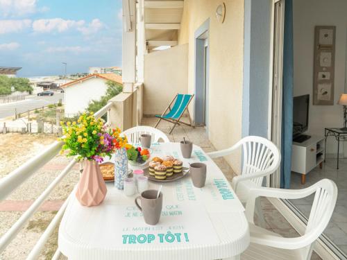 uma mesa branca com comida e flores numa varanda em Apartment Patguyflor by Interhome em Mimizan-Plage