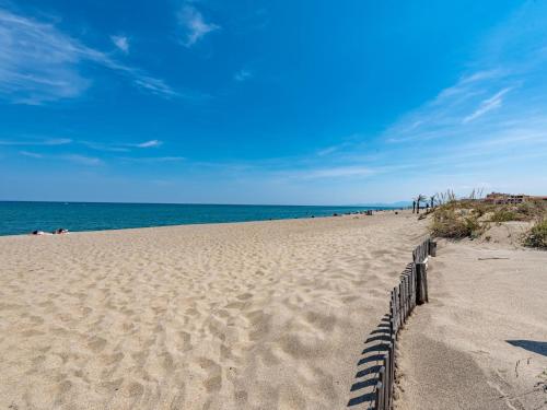 une plage de sable avec une clôture en face de l'océan dans l'établissement Apartment Amphitrite-1 by Interhome, au Barcarès
