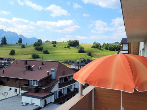 an orange umbrella on a balcony with a green field at Apartment Ladis-3 by Interhome in Ladis