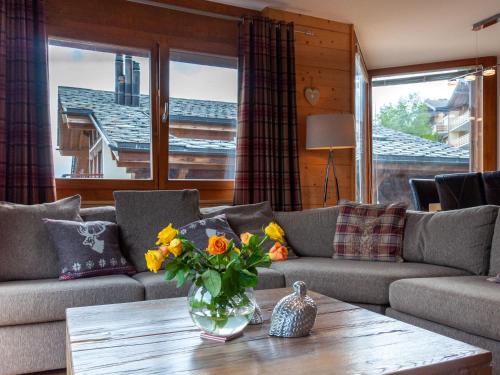 a living room with a couch and a table with flowers at Apartment Les Cimes Blanches B 401 by Interhome in Nendaz