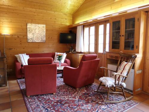 een woonkamer met een bank en stoelen en een tv bij Chalet Les Clarines by Interhome in Grimentz