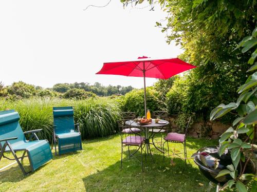 une table et des chaises avec un parasol rouge dans l'herbe dans l'établissement Holiday Home L'Hirondelle by Interhome, à Kermerchou