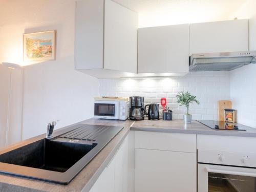 a kitchen with white cabinets and a sink at Apartment Les Hauts des Issambres-12 by Interhome in Les Issambres