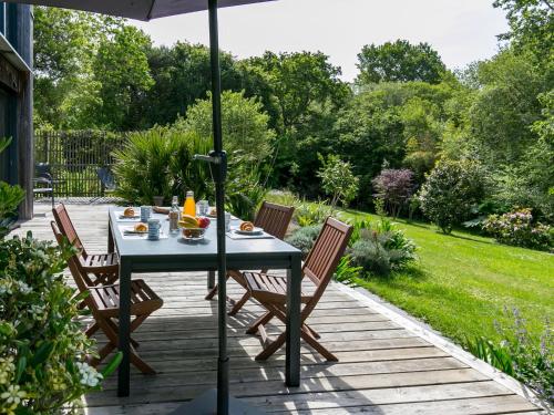 a table with chairs and an umbrella on a patio at Chalet Ty Coat by Interhome in La Forêt-Fouesnant
