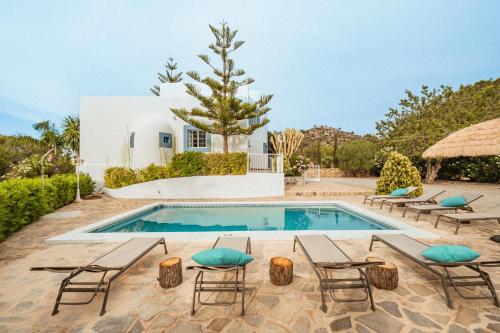a villa with a swimming pool and chairs at Villa Sa Bassa, Amazing seaviews and great Pool in Portinatx