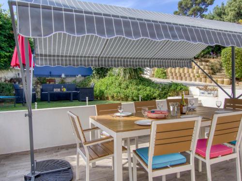 a wooden table and chairs under an umbrella on a patio at Holiday Home De Manou - SFP135 by Interhome in Six-Fours-les-Plages