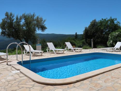 a swimming pool with two chairs and a table at Apartment Magnolia - RAC167 by Interhome in Rabac