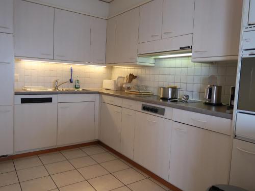 una cucina bianca con armadietti e elettrodomestici bianchi di Apartment Montreux - Panorama by Interhome a Montreux
