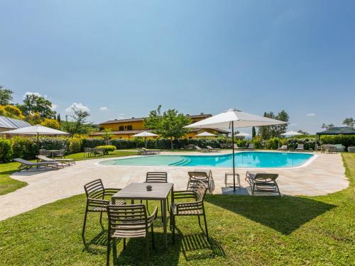 uma mesa com cadeiras e um guarda-sol ao lado de uma piscina em Apartment Il Casale by Interhome em Limite