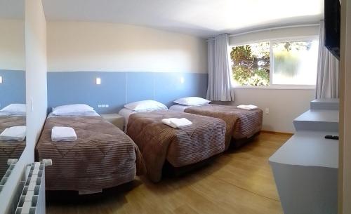 Una habitación de hotel con tres camas y una ventana. en Pousada Rastro da Serra, en Bom Jardim da Serra