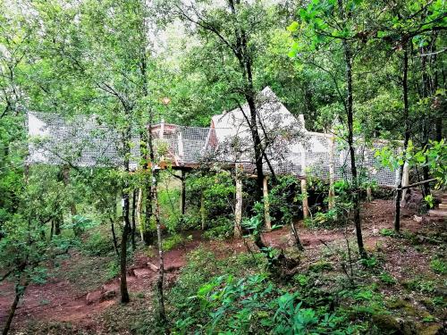 une maison avec un pont au milieu d'une forêt dans l'établissement TENTE HIBOU INSOLITE AVEC FILET DE DETENTE Camping lou cantou cevenol, à Anduze