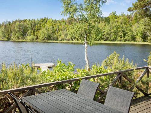 uma mesa de madeira e 2 cadeiras sentadas num deque com vista para um lago em Chalet Kasen Sjökanten by Interhome em Färgelanda