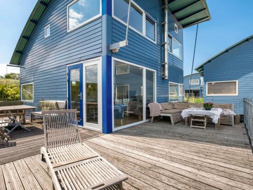 a blue house with a wooden deck with a bench at Holiday Home Rietwoning 16 by Interhome in Anjum