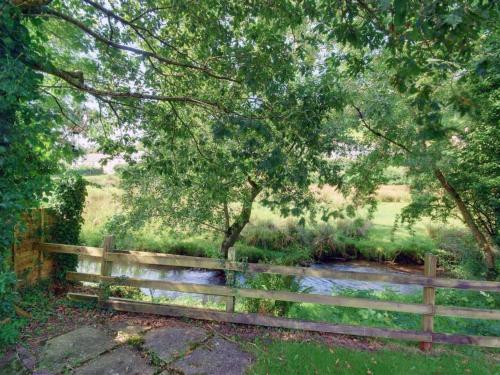 a wooden fence in front of a pond at Holiday Home Mill Court by Interhome in Swimbridge