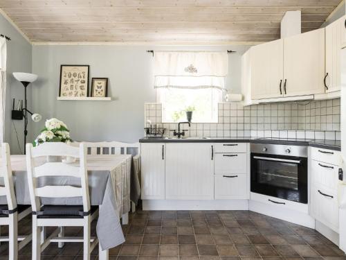 eine Küche mit weißen Schränken sowie einem Tisch und Stühlen in der Unterkunft Holiday Home Skärvudde Huset - SND084 by Interhome in Kalvsvik