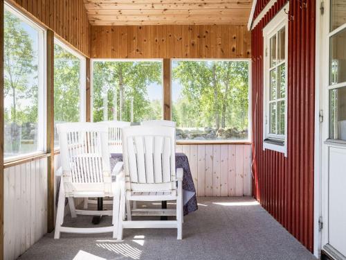 zwei weiße Schaukelstühle auf einer Veranda mit Fenstern in der Unterkunft Holiday Home Skärvudde Huset - SND084 by Interhome in Kalvsvik