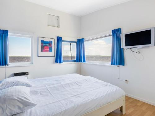a white bedroom with blue curtains and a bed at Holiday Home Jachthaven Oostmahorn by Interhome in Anjum