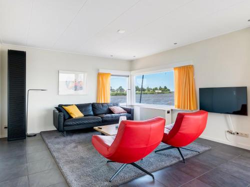 a living room with red chairs and a couch at Holiday Home Jachthaven Oostmahorn by Interhome in Anjum