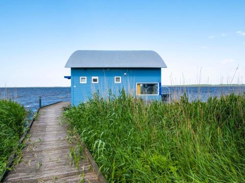 a blue house on the beach next to the water at Holiday Home Jachthaven Oostmahorn by Interhome in Anjum