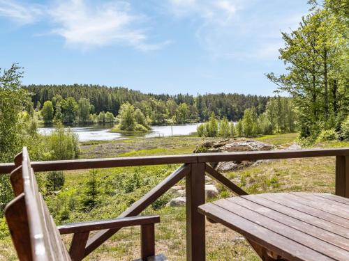 a wooden bench sitting on a porch overlooking a river at Holiday Home Erikstorp Fyran - B in Olofström