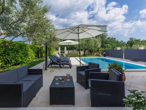 a patio with chairs and an umbrella and a pool at Apartment Mir by Interhome in Vošteni