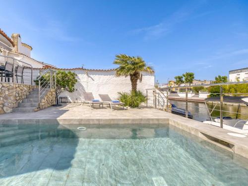 a swimming pool with two chairs and a palm tree at Holiday Home Sunset by Interhome in Empuriabrava