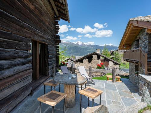 un patio con tavolo, sedie e montagne di Chalet Chalet les Combes by Interhome a Introd