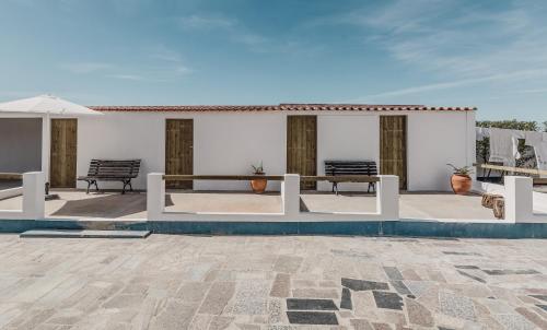 a patio with two benches and a table at Humus Farm in Águas de Moura