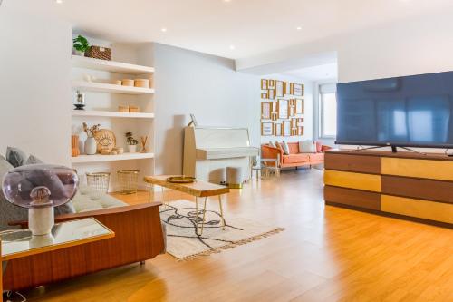 a living room with a flat screen tv and a piano at 3-bedroom Apt with Private Patio in Cacilhas by Lisbeyond in Almada